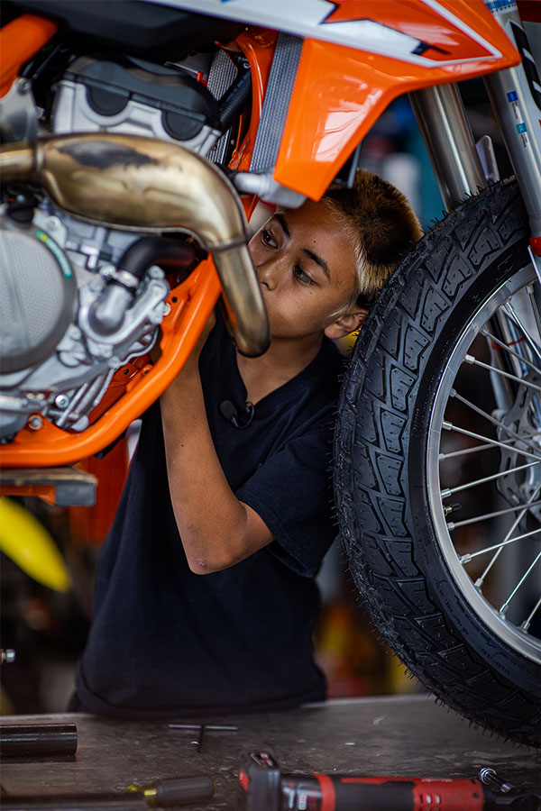 Kage working on his motorcycle in a garage.